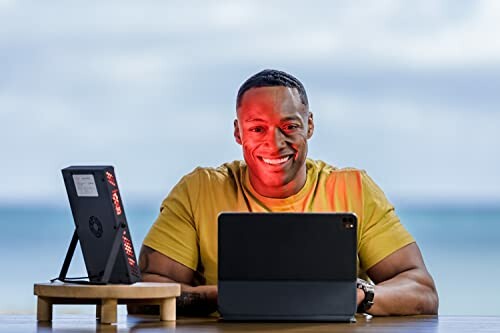 Man using a tablet with a red light device nearby